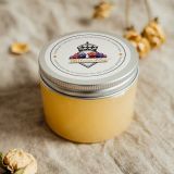 There is a glass candle jar with a custom printed label reading: “Tasty Candles”. The label is white and affixed to a metal jar lid.