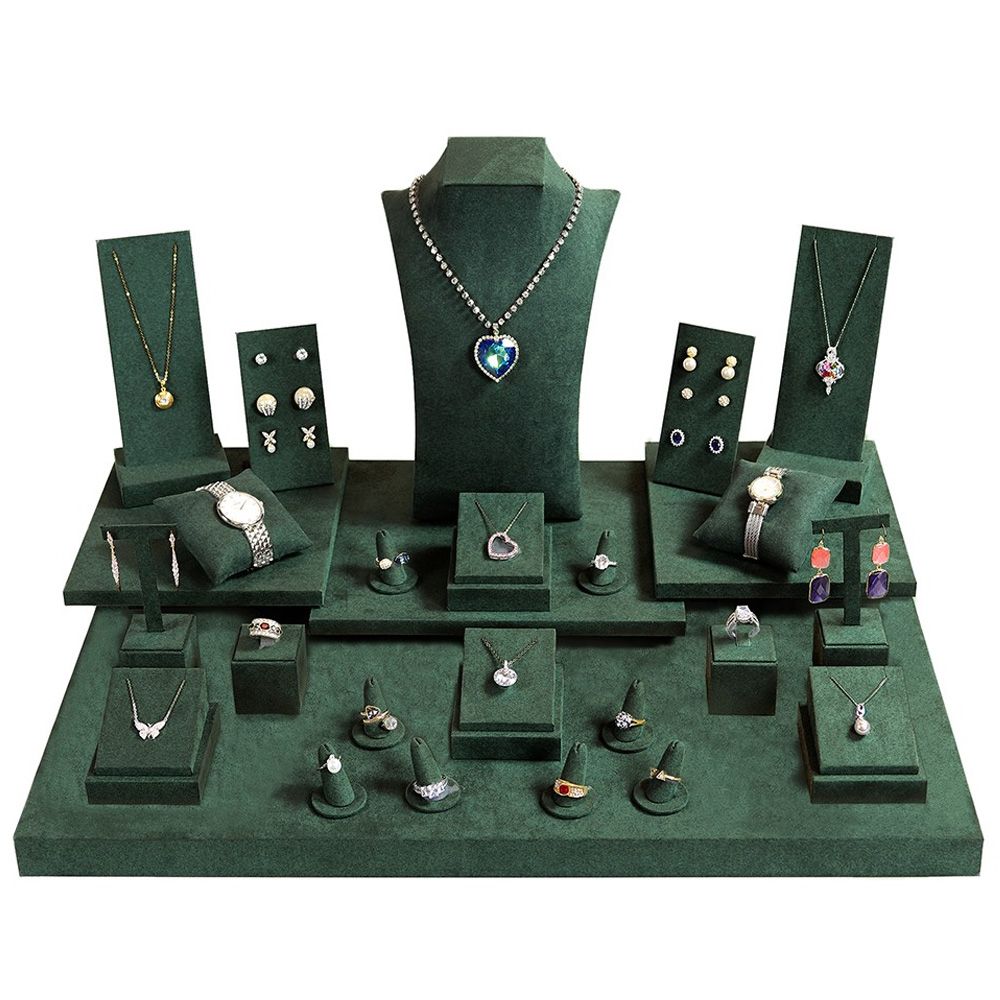 A 27-piece jewelry display set in luxurious dark green suede, featuring various stands and holders for rings, necklaces, bracelets, and earrings.